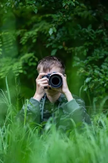 Kajtek fotografujący przyrodę wśród zieleni
