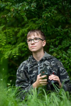 Kajtek z aparatem fotograficznym wśród zieleni